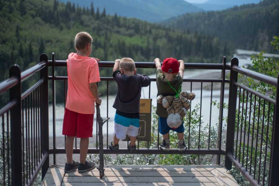 Boy who has connection with animals holds on to railing that over looks body of water with two brothers