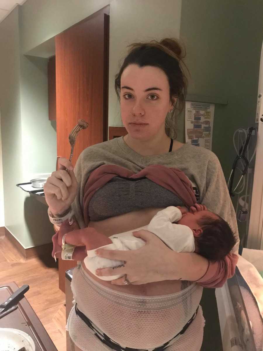 Woman who just gave birth breastfeeding newborn while holding fork with food on it