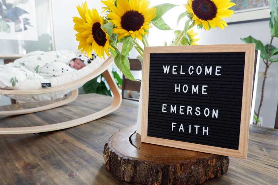Adopted newborn sleeping at home next to sign saying, "Welcome Home Emerson Faith"