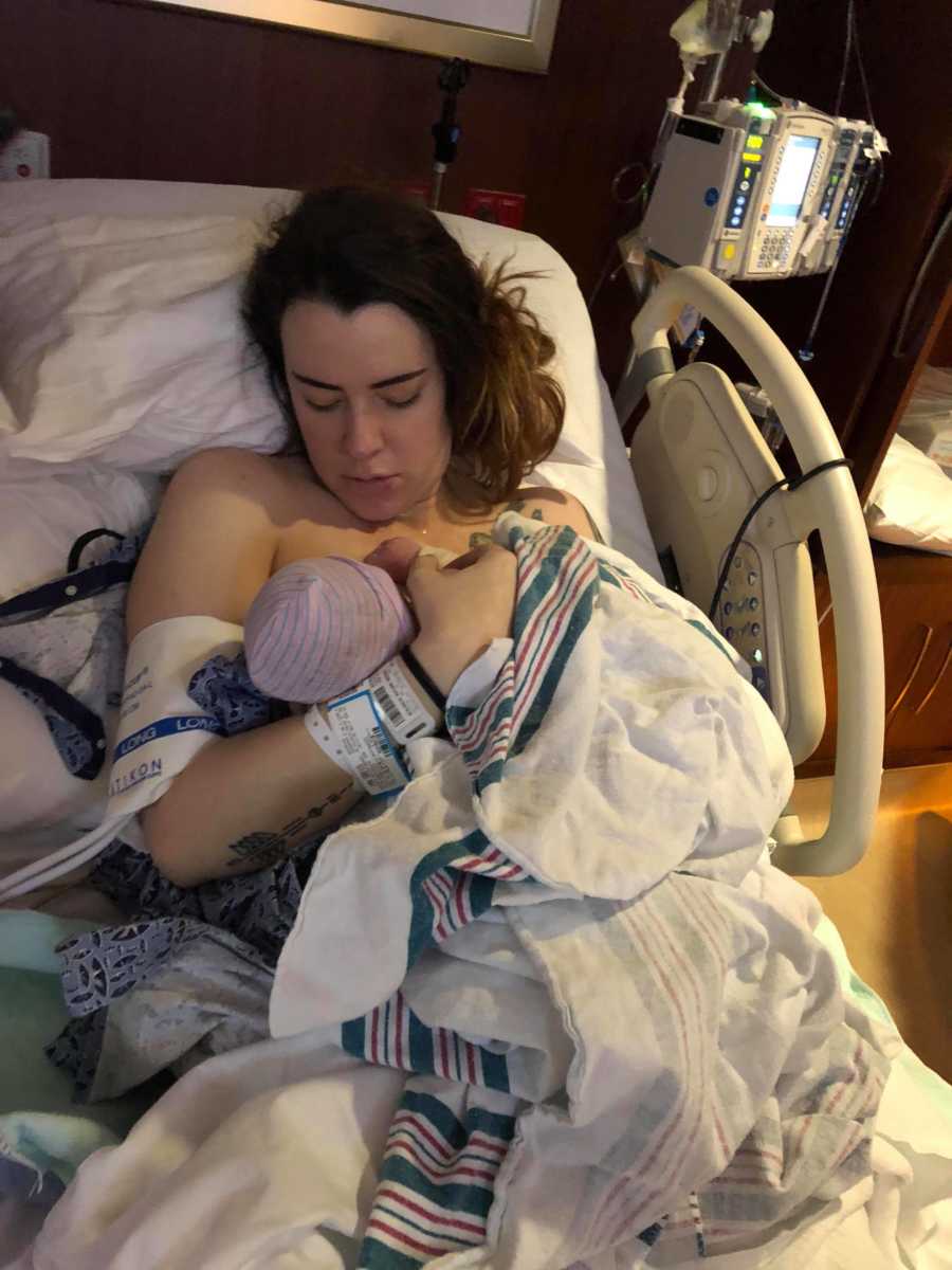 Woman who discusses the difficulties after giving birth breastfeeds in hospital bed