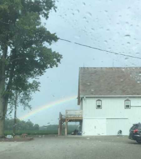 Rainbow above barn on wedding day showing bride her father is with her