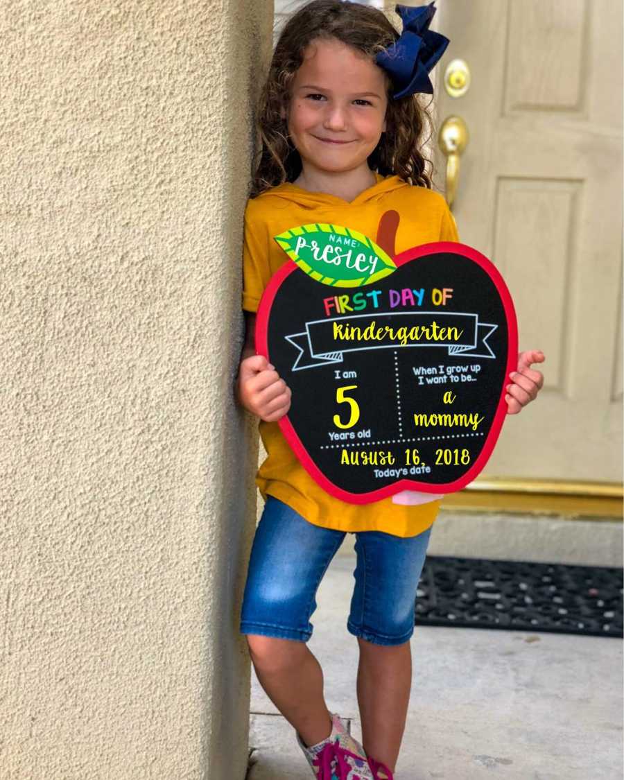 Little girl whose mother is scared for her to start school holds sign saying, "First day of kindergarten"