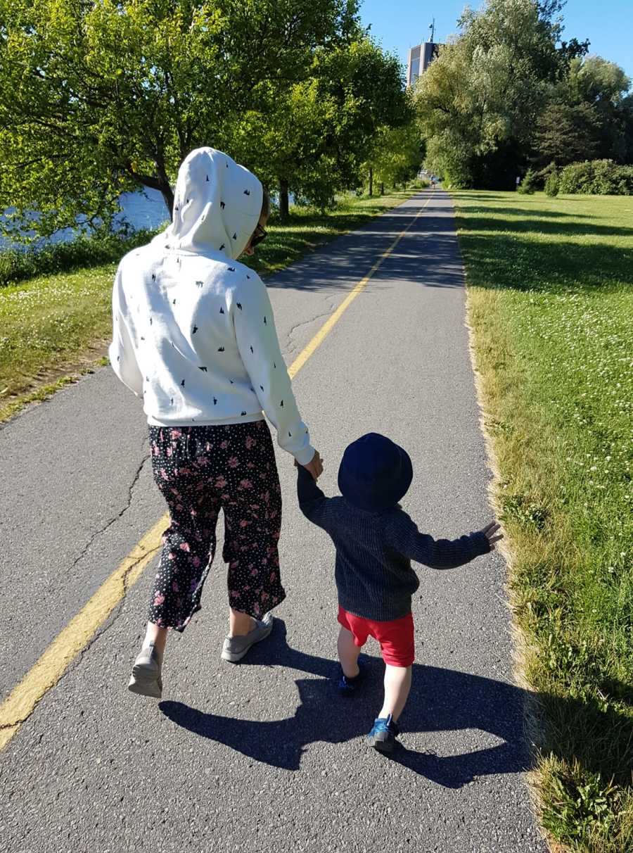Mother who suffered from postpartum depression walks holding hands with toddler son 