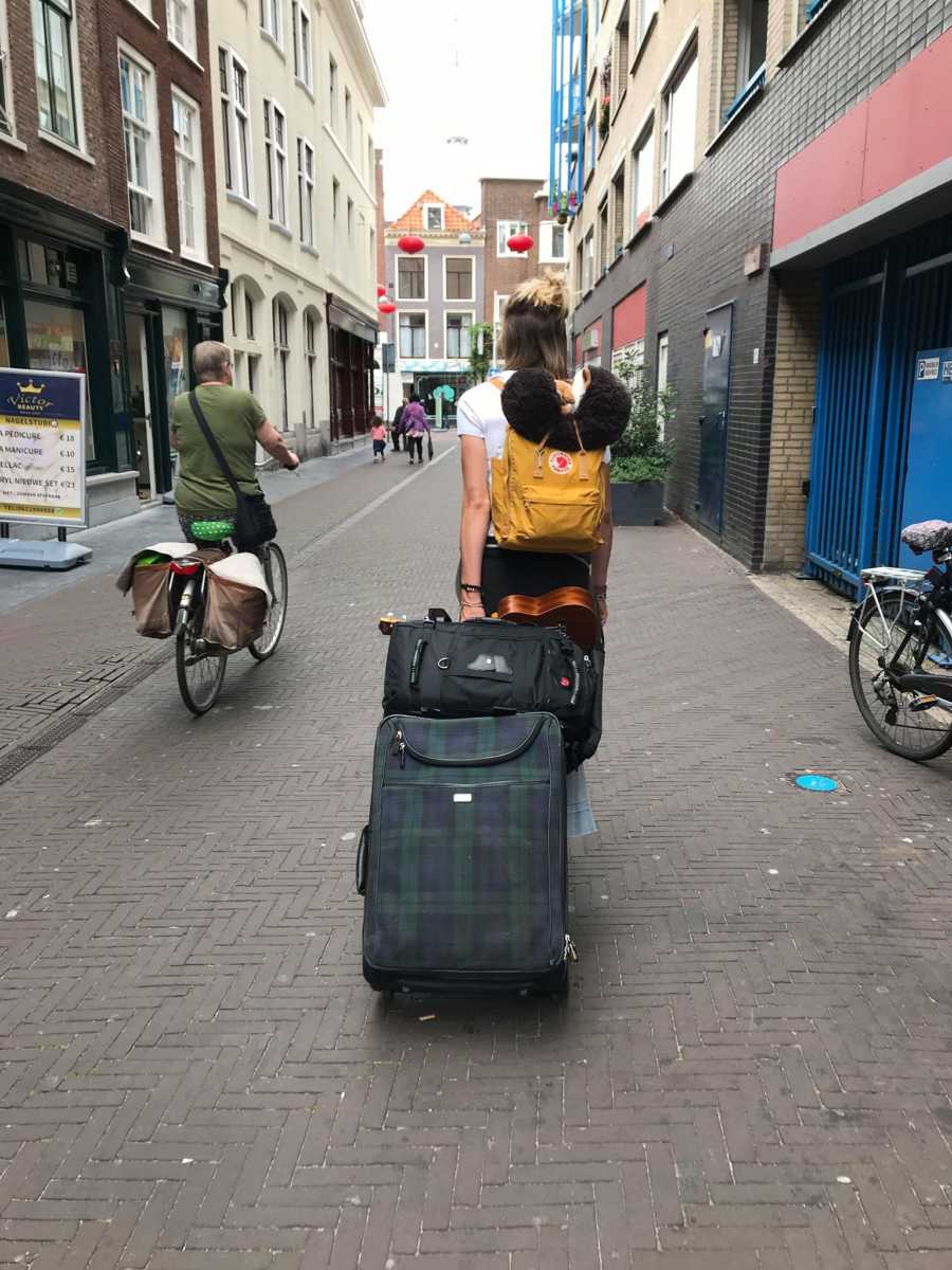 Teen walking streets of Netherlands with luggage as she moves there for college