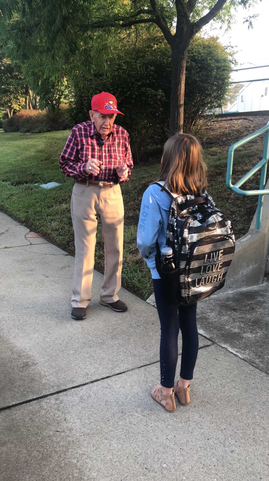 Old man who stands outside middle school to encourage kids stands giving young girl advice