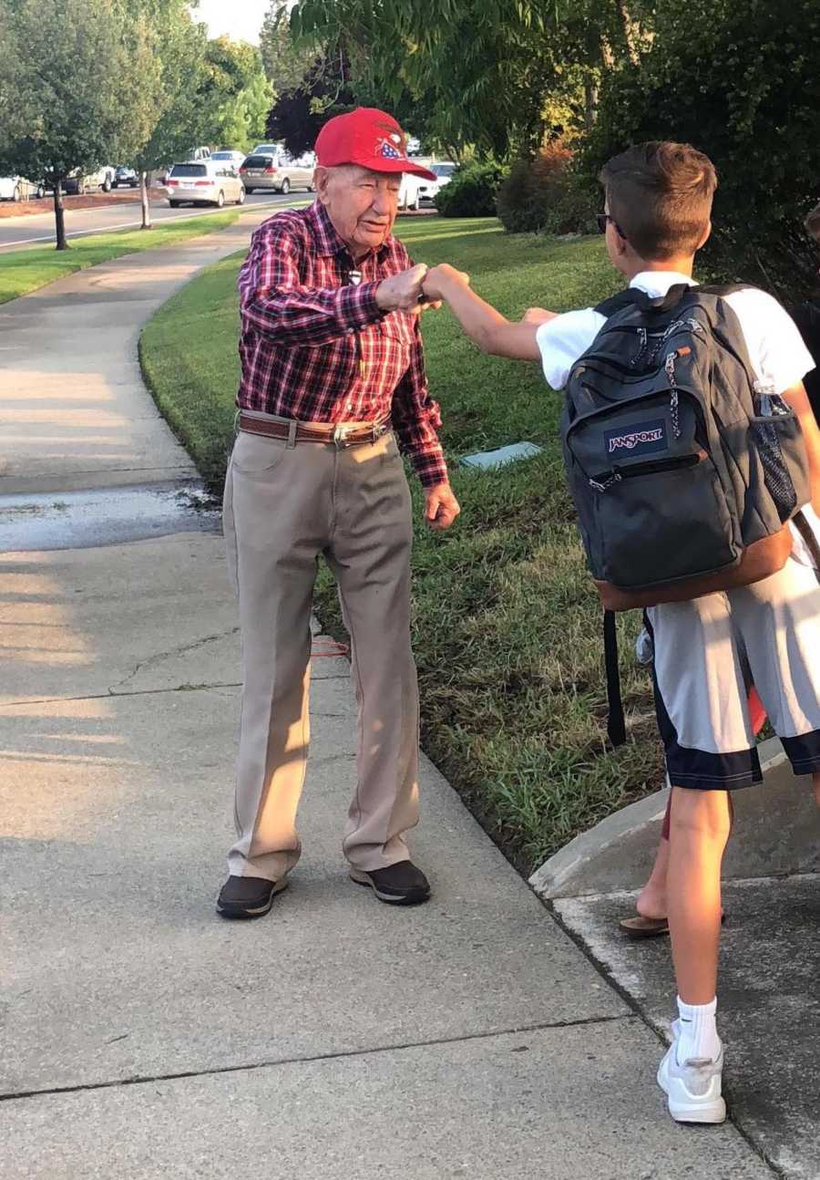 Old man who stands outside middle school to encourage students fists bumps teen boy