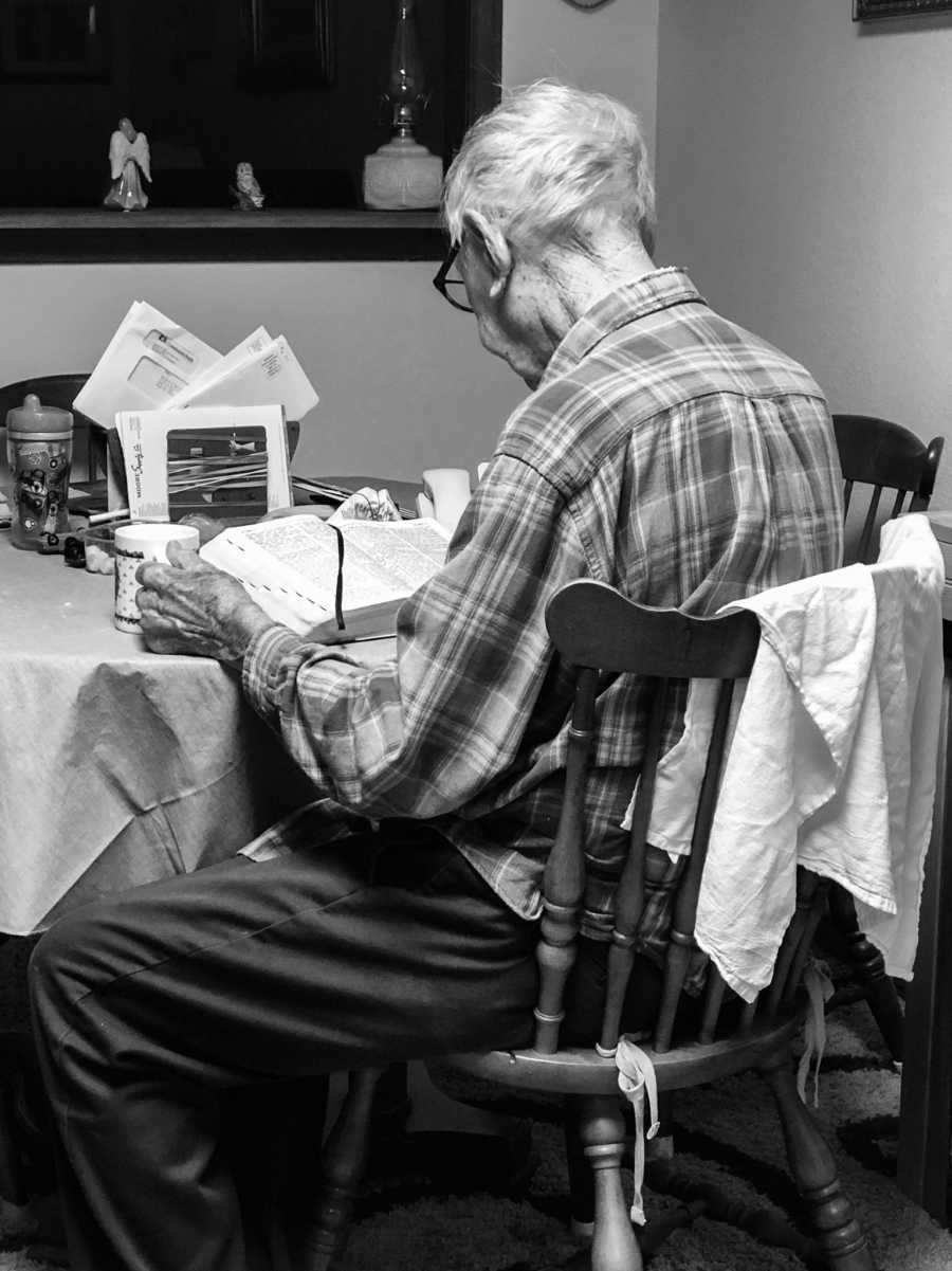 Elderly man sitting at table with cup of coffee reading