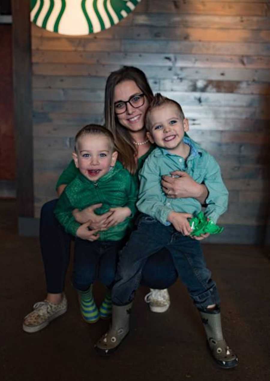 Mother who feels stressed out by her kids smiles with her young boys in her lap