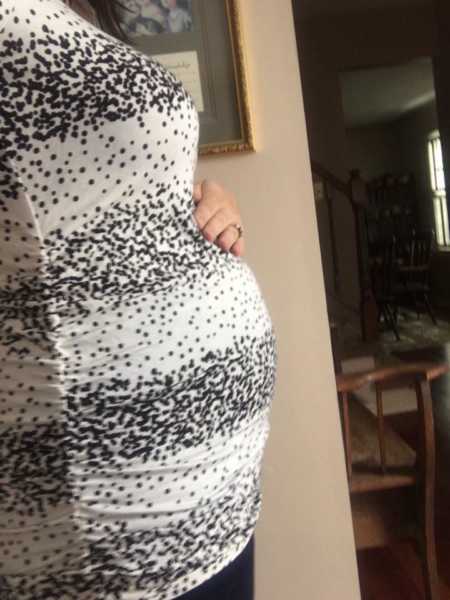 Side view of pregnant woman holding her stomach