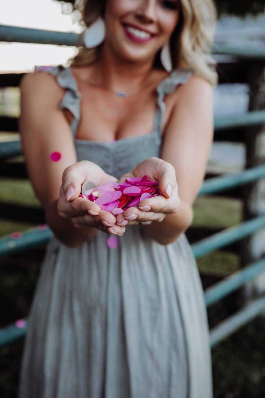 Up close of recently single dog mom holding pink confetti from pinata