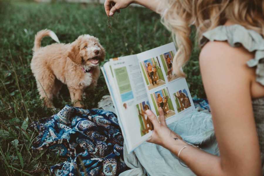 Recently single dog mom holds book while trying to teach puppy trick