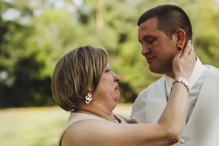 Mother with breast cancer cries as she holds oldest sons neck at his wedding