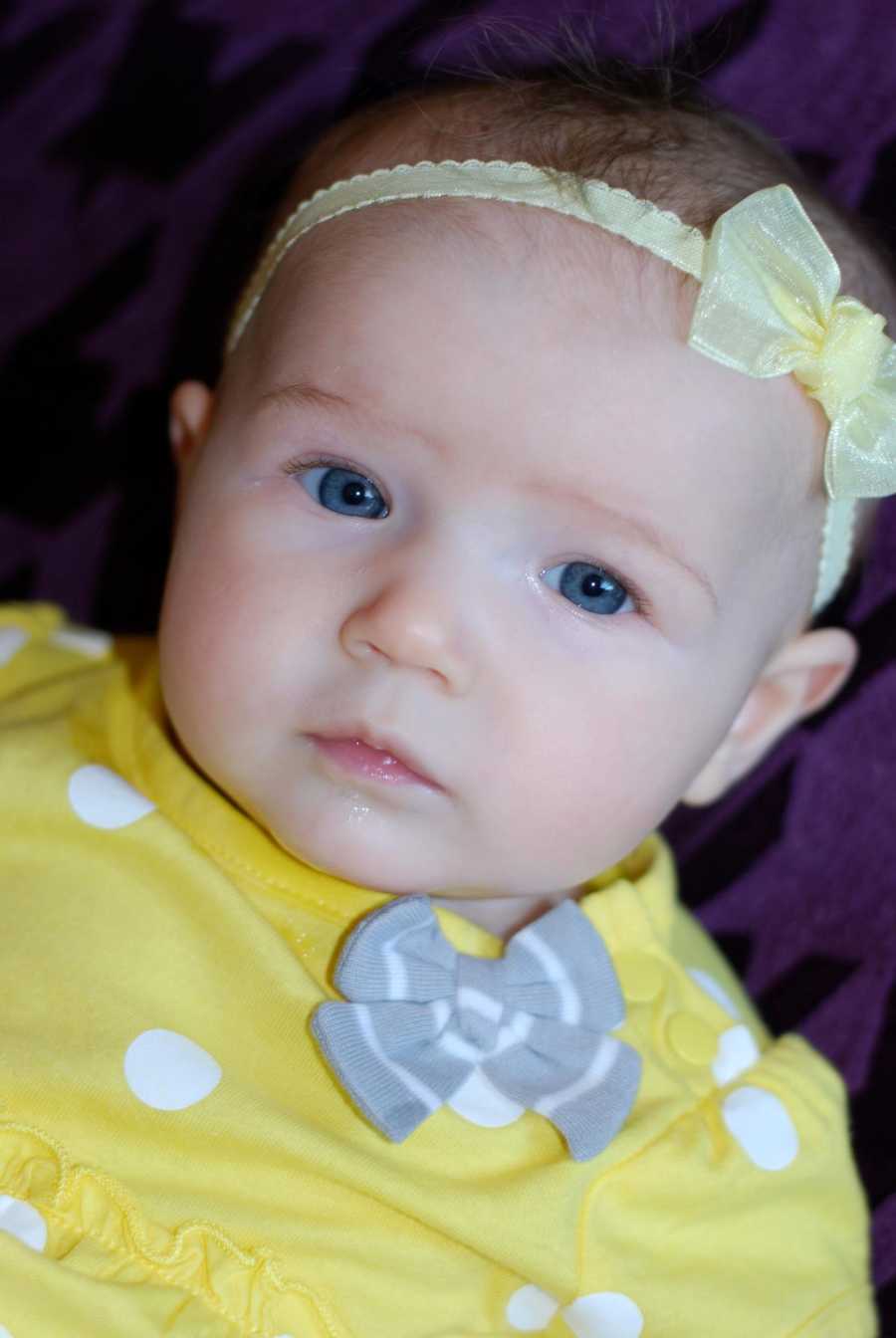 Close up of baby in yellow onesie with yellow headband whose mother is scared for her to start school
