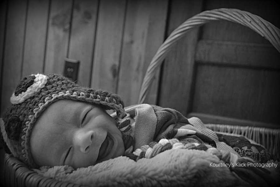 Baby with chromosome 7 inversion smiling while sleeping in basket