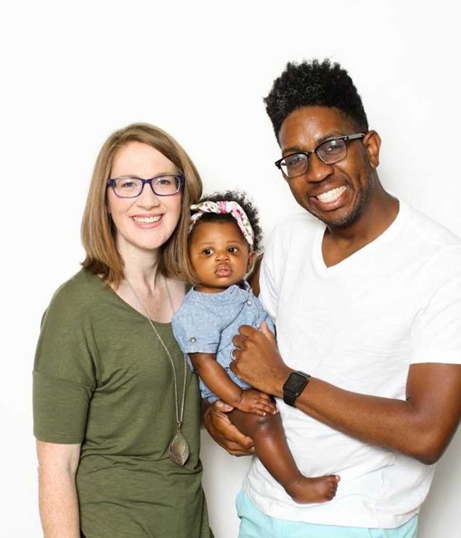 Mother and father smile holding adopted daughter they paid for with money they won on game show