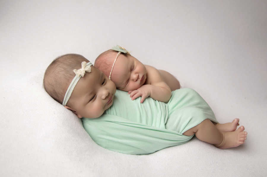 Newborn swaddled in green blanket lays next to newborn her parents adopted from couple at church