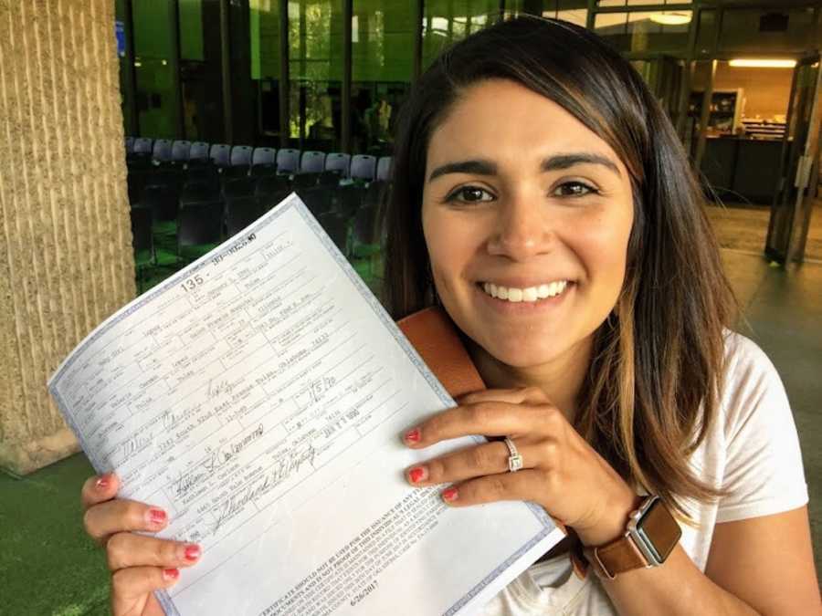 Woman who was adopted at birth holds up birth certificate she tracked down to find birth parents