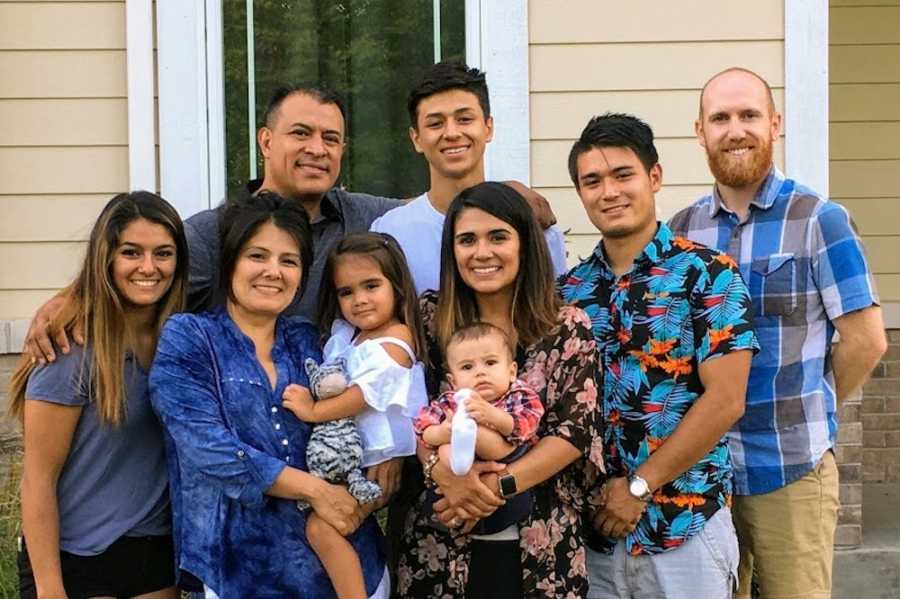 Woman who was adopted at birth stands with her two children, husband, birth parents, and three siblings