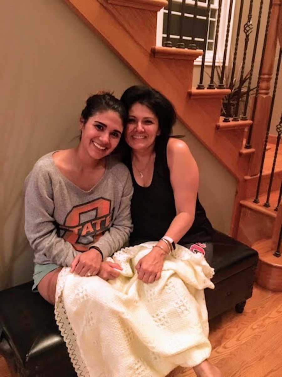 Woman sits on bench under stairs with birth mother in home