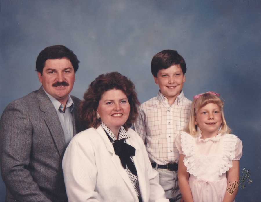 Husband and wife sit smiling with adopted son and daughter who would find her birth parents later in life