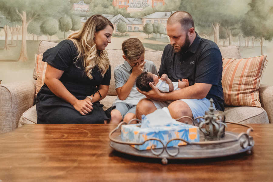 Young boy cries while looking at his newborn foster sibling