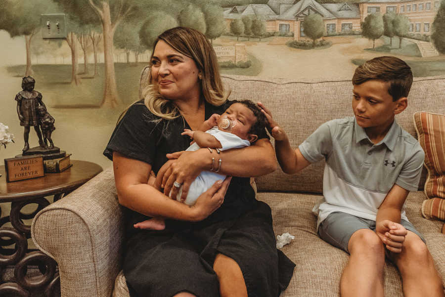 Foster mom smiles while biological son pets foster son's hair