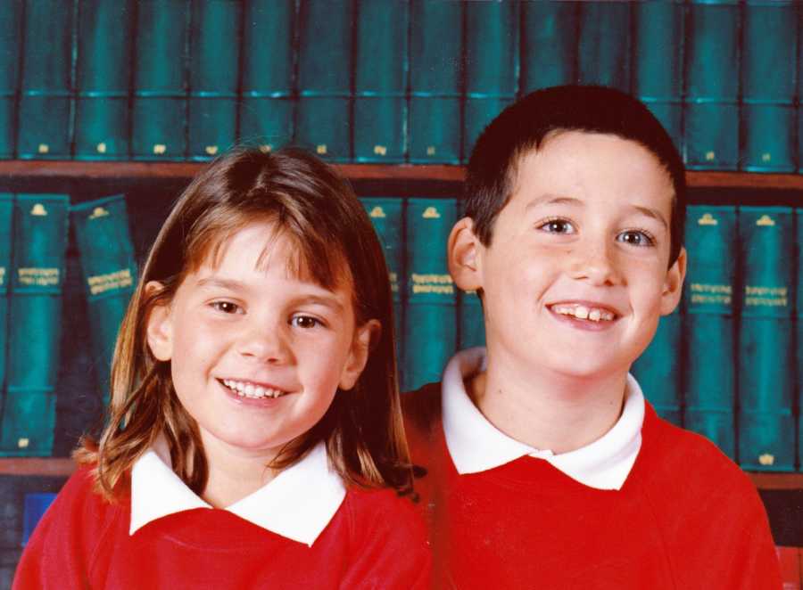Brother and sister who were adopted smile in front of book shelf