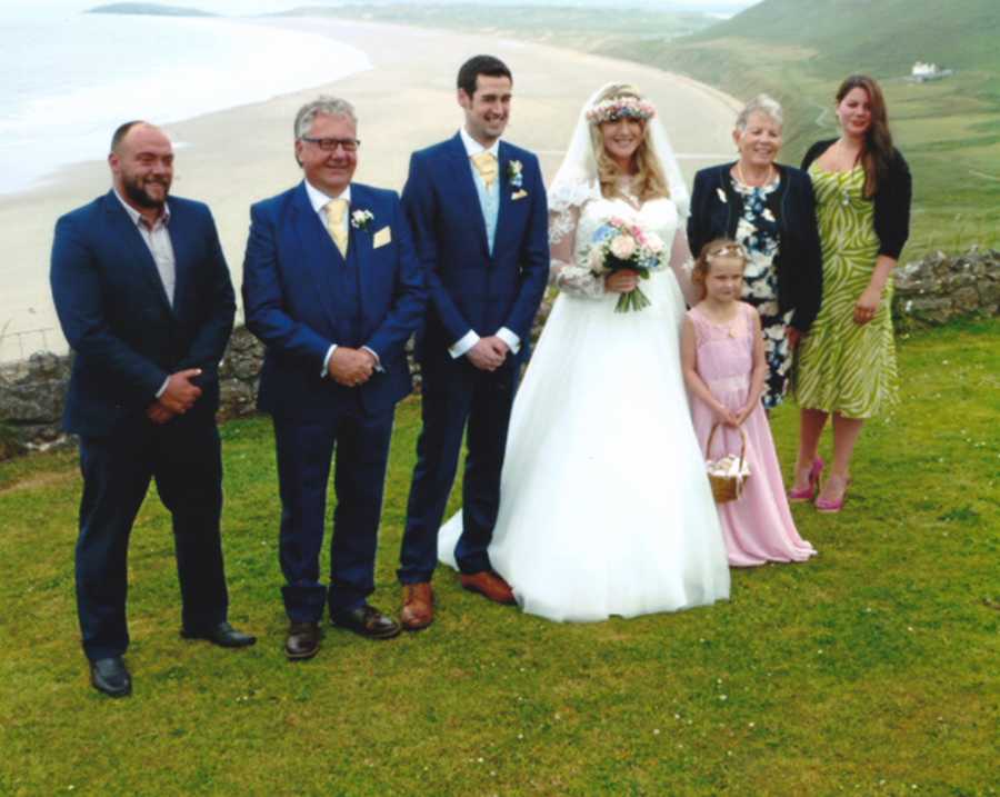 Adopted son on his wedding day with wife and her child beside his adopted parents, sister, and brother in law