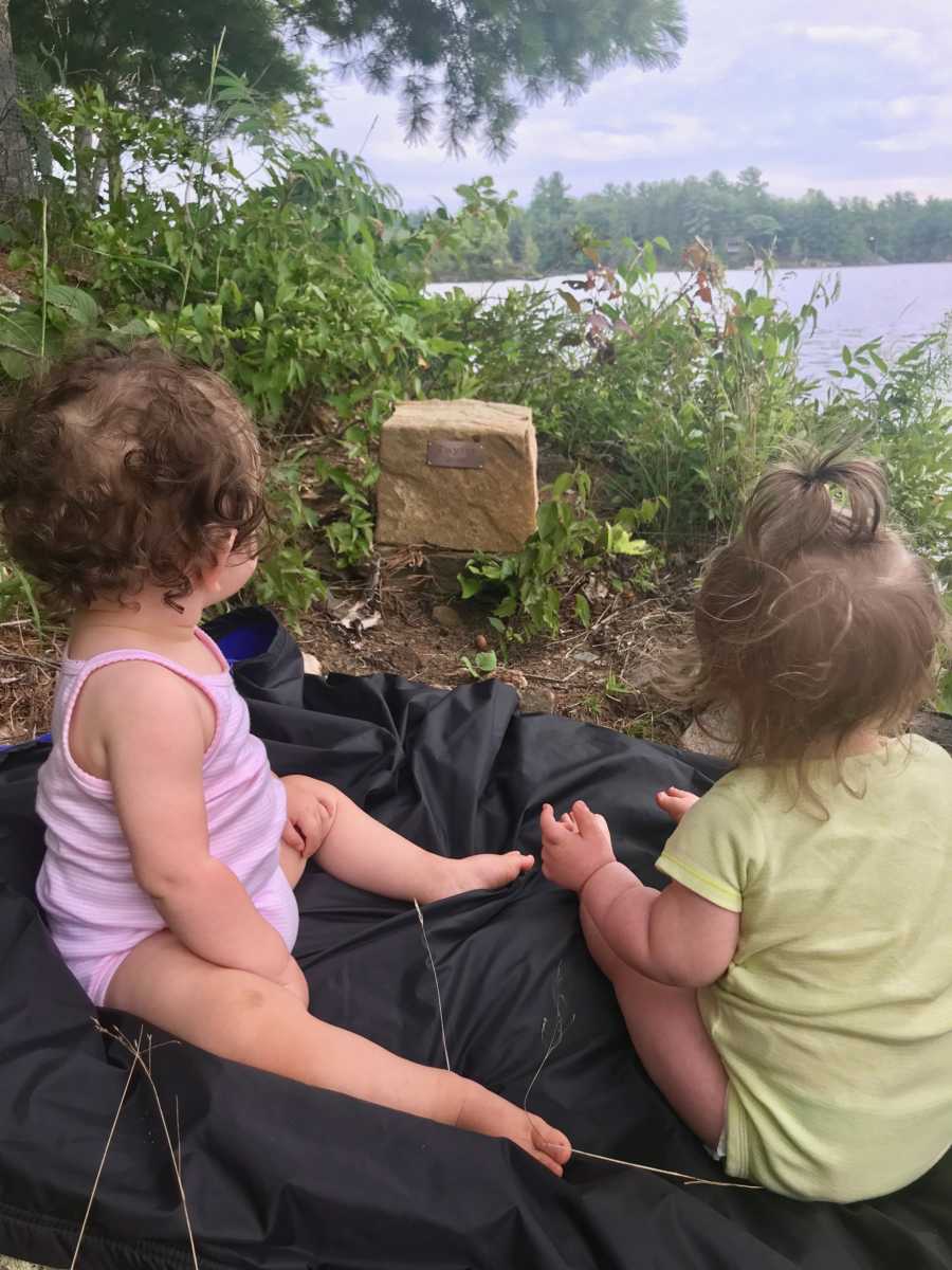 Twins of woman who struggled to get pregnant sit on ground next to rock with plaque on it saying, "Taylor 2016"