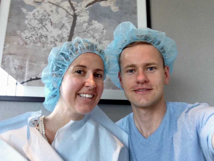 Husband and wife who struggled to get pregnant smile in selfie wearing scrubs at fertility clinic