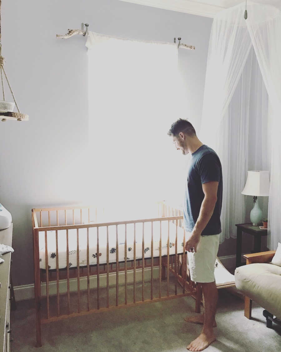 Man standing over crib in nursery