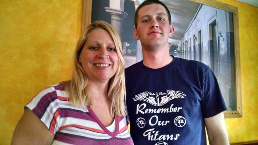 Woman who will later in life have breast cancer stands smiling with teen son