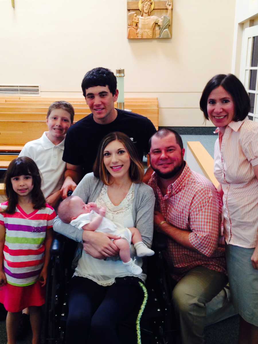 Woman with Superior Mesenteric Artery Syndrome sits in wheelchair holding baby surrounded by family members