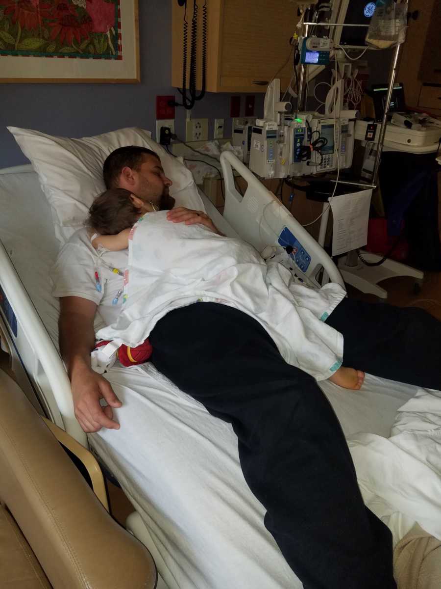 Little boy with cancer sleeps on father's chest who is asleep in hospital bed