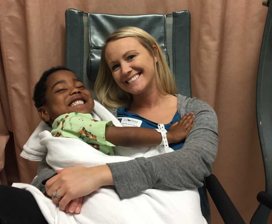 Woman sits in hospital chair with her adopted son smiling in her lap