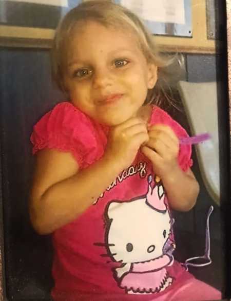 Little blonde girl smiles for a photo in a pink Hello Kitty t-shirt