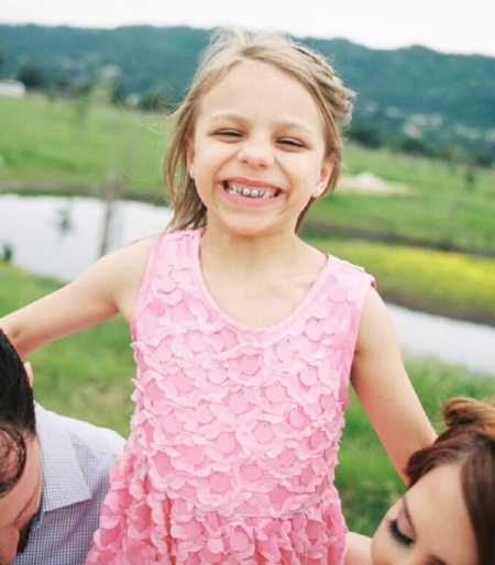 Little girl smiles big in frilly pink dress during family photoshoot