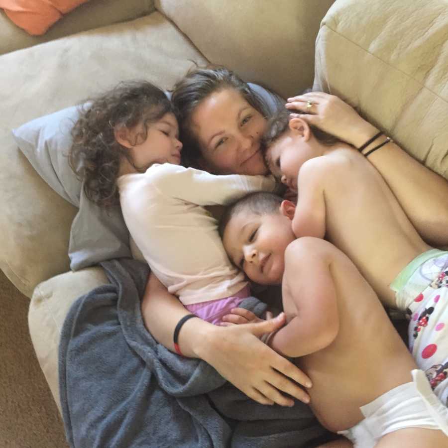 Woman who only ever wanted to be a mother lays on couch with her twin girls and 2 year old boy she has custody of