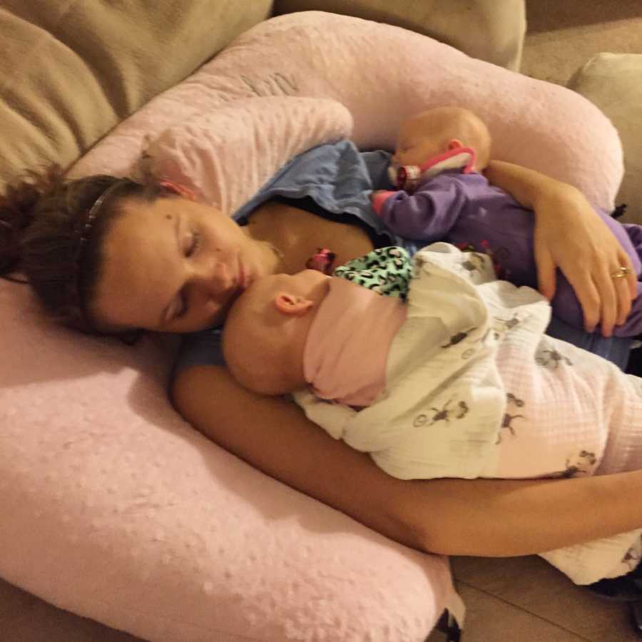 Young mother asleep with twin girls asleep in both of her arms