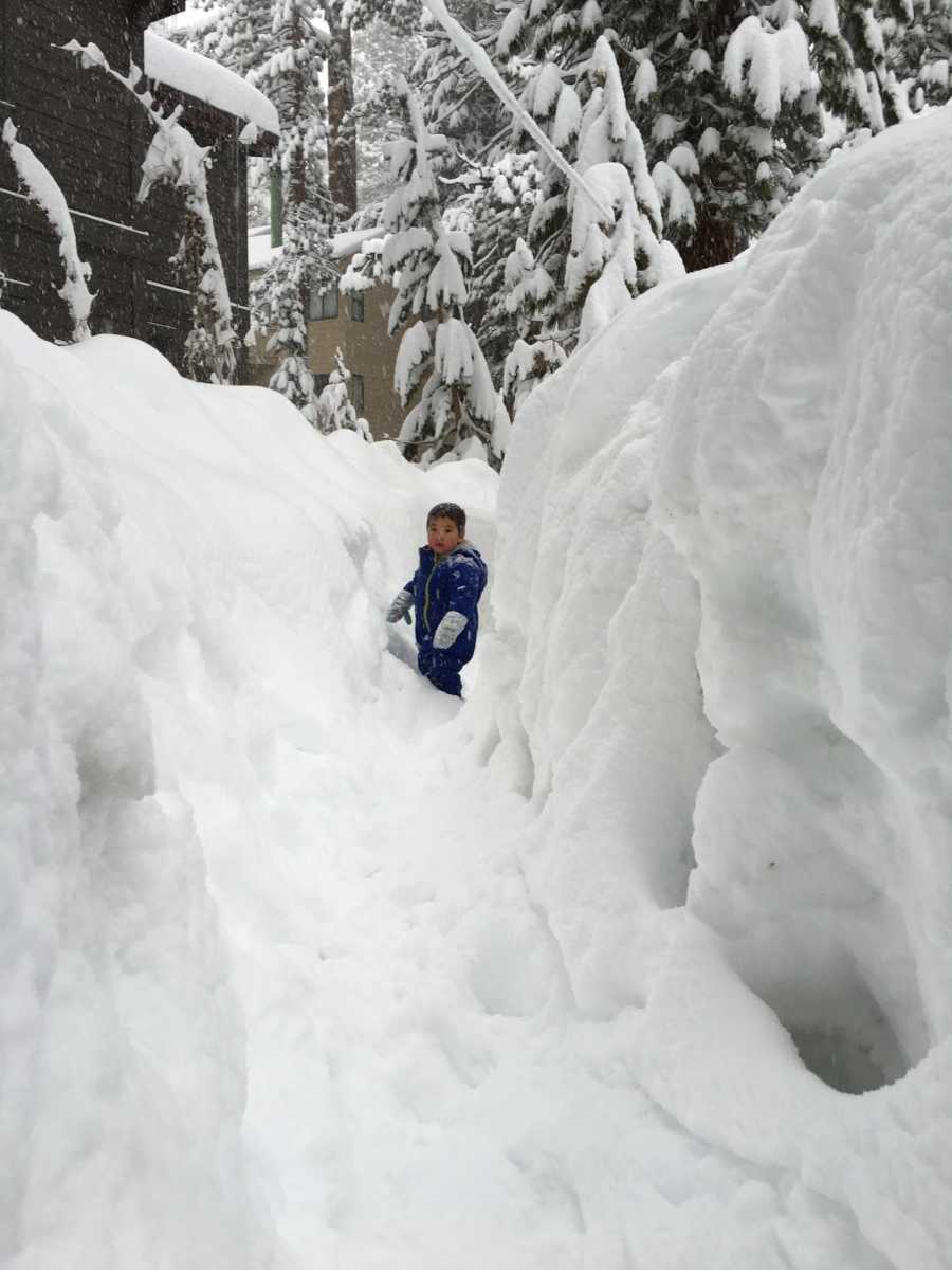 Little boy in foster care playing in between tall piles of snow