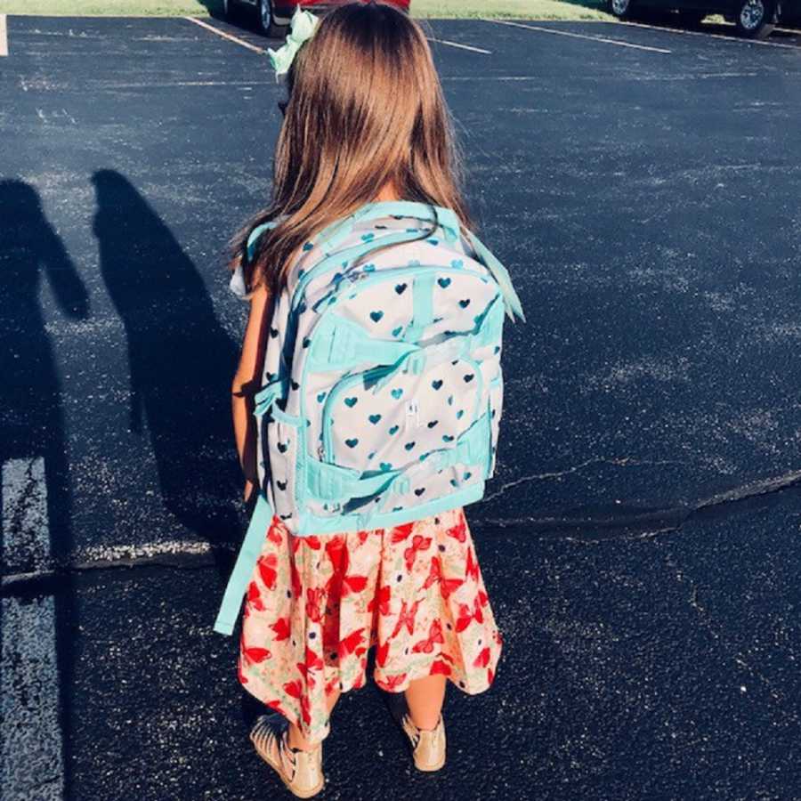 Surviving triplet stands with backpack on ready for first day of school