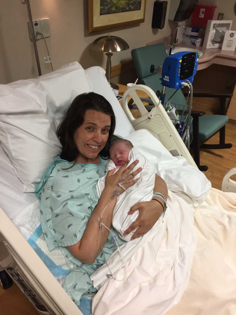 Woman who can't breastfeed lays in hospital bed holding newborn