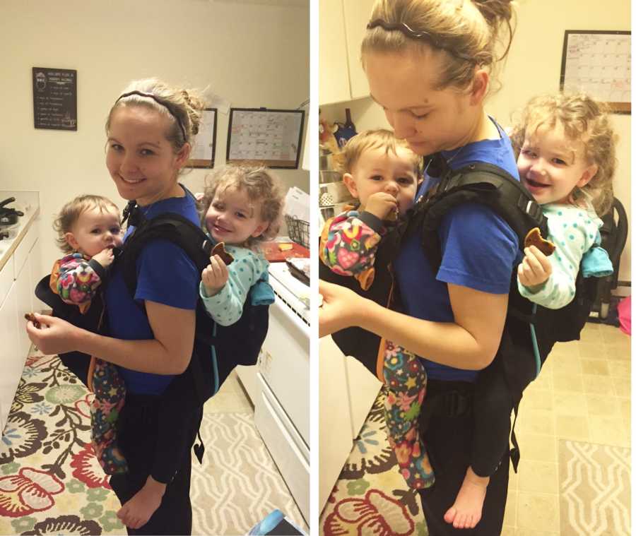 Young mother of two stands in kitchen with one twin strapped to her chest and other to back