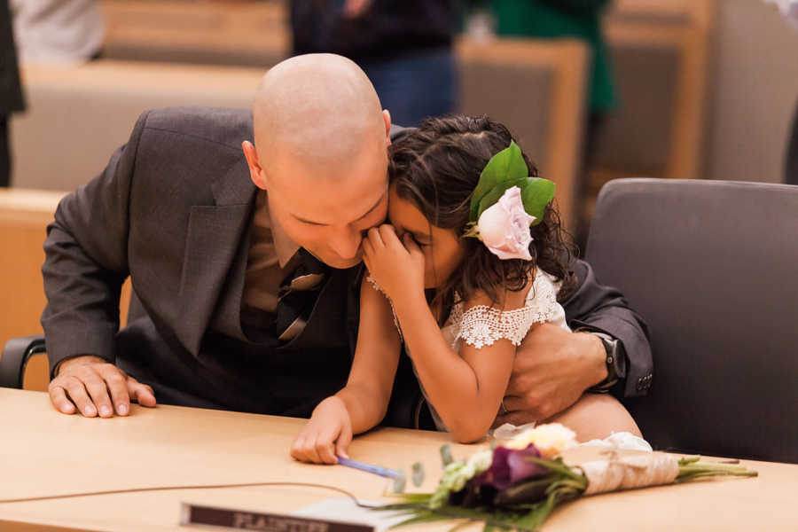 Foster father holding onto her daughter that he just adopted at court