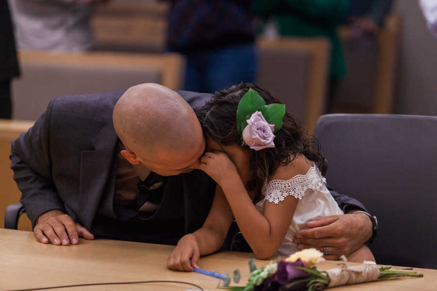 Father holds adopted daughter who is crying at adoption court
