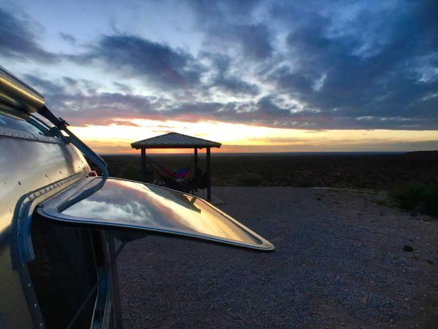 Airstream with window open with sunset in background