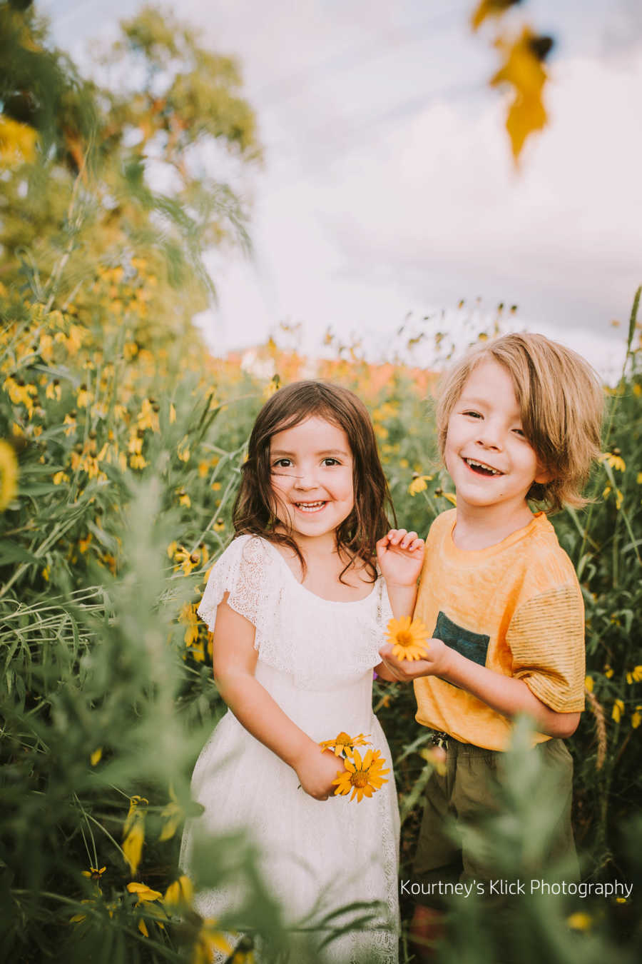 Boy with chromosome 7 inversion smiling in sunflower field next to little sister