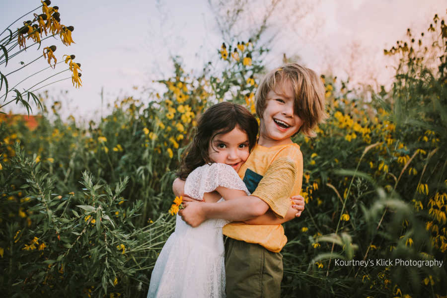 Boy with chromosome 7 inversion hugging little sister in sunflower field