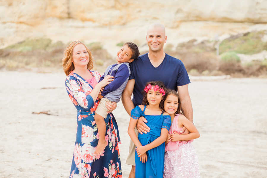 Husband and wife smile in desert landscape with three foster children