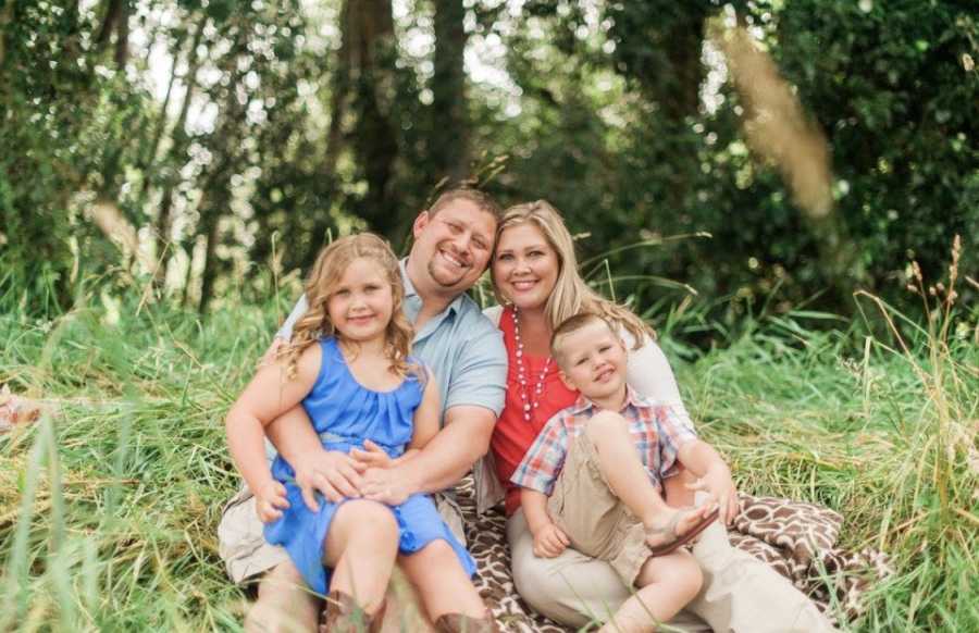 Woman who was closet drunk sits in grass next to husband with daughter and son in their laps